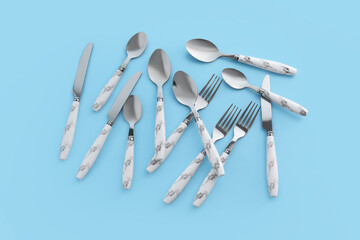Stainless steel cutlery with plastic handles on blue background