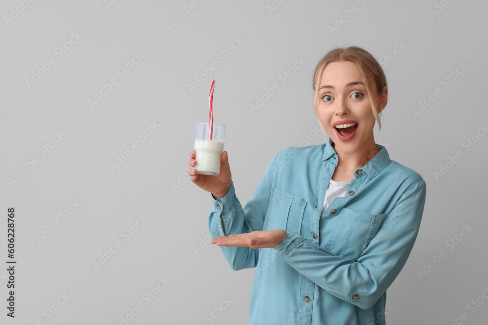 Poster Young woman with glass of milk on grey background