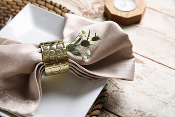 Beautiful table setting with candle and gypsophila flowers on light wooden background, closeup