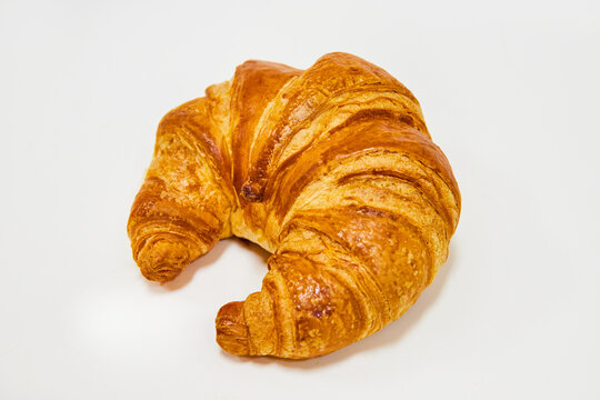 Side view of fresh backed crescent shaped croissant on white background