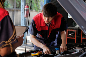 Two professional automotive mechanical partners check and repair an EV car battery and hybrid engine at a maintenance garage, expert electric vehicle service, and fixing occupations auto industry.