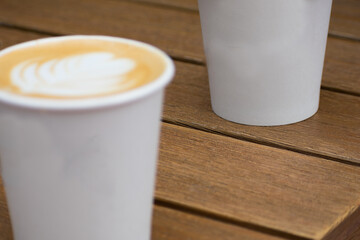 Two coffee cups with latte art sitting on a wooden table - abstract cafe background