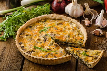 a cheese quiche with chicken arugula and garlic on a table