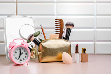 Morning routine. Golden cosmetic bag in the bathroom. Morning pills. Mirror, comb, foundation, makeup brushes, face massage oil, massage roller