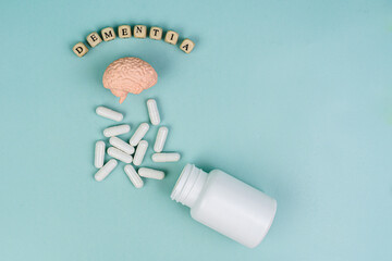 Brain and pills on a blue background. Lettering dementia.