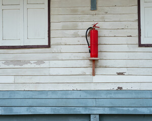 Red fire extinguisher installed at the wall of old wooden building