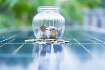 Coin and blurred solar panel cell on background with copy space. Money business in renewable energy...