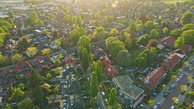 Flying over a stunning suburban neighborhood at golden hour in summer. The sun flares into the camera
