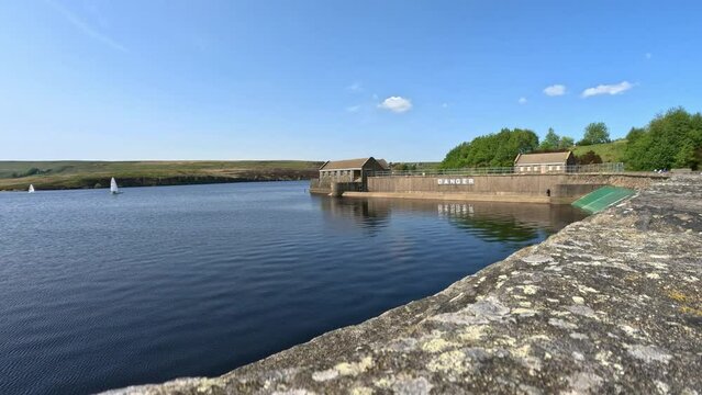 English lake with lakeside buildings and the word danger painted on the lakeside wall. Reservoir UK