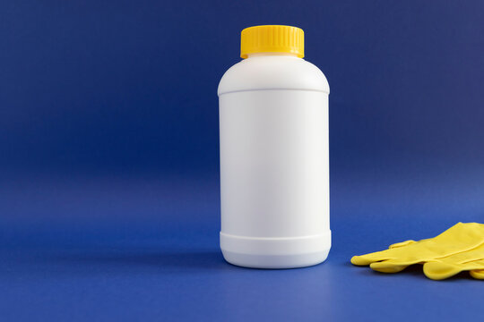 Pipe Plumber Drain Granules in White Plastic Bottle With Yellow Cap, Rubber Glove On Blue Purple Background. Clog Cleaner, Enzymes, Prevention of Blockages In Traps. Horizontal plane, Copy Space