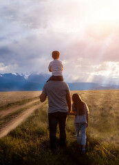 Father and children on a walk in the mountain steppe at sunset.