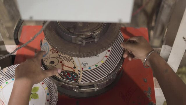 disposable paper plastic free recycle material factory press close up with female Indian worker hand controlling the machinery