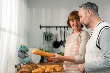 Caucasian senior elderly couple spend time together in kitchen at home.