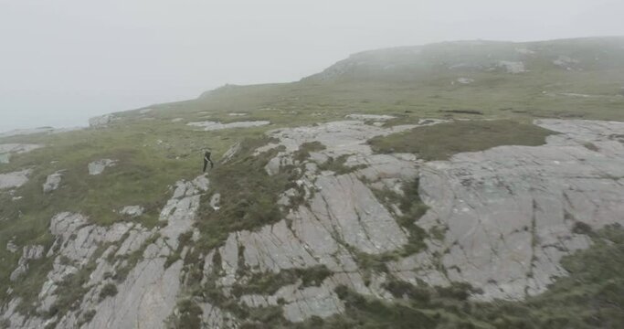 Drone panning shot of a hiker walking the coastline of the Scottish Highlands, outside Durness rocky and moss terrain