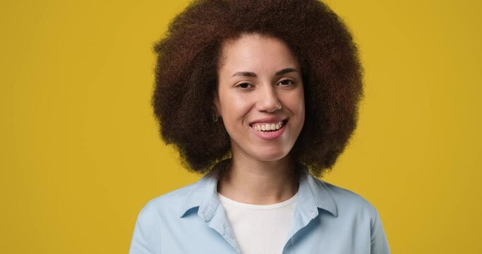 Smiling attractive african american woman looking at camera listening to someone and nodding with agree standing over orange studio background