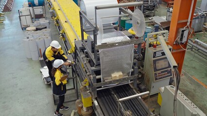 Two industrial factory workers using tablet for working in plant inspect the machines for metal...