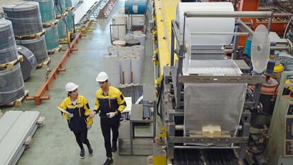 Industrial engineers men and women in plant working and discuss while walk through metal industry factory, Manufacturing industry equipment