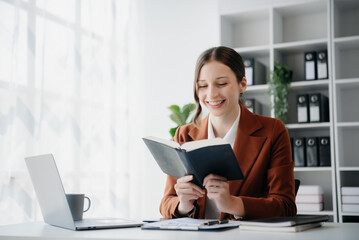 woman reading book while sitting at in home office