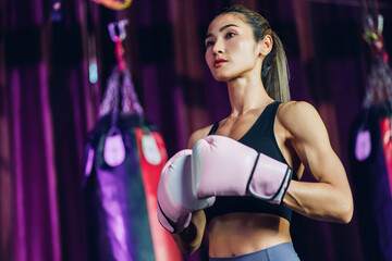 Naklejka premium Female Boxer training in Boxing Club. Woman Boxing fighters training at gym. Strong muscular woman practicing box in pink boxing gloves in gym.