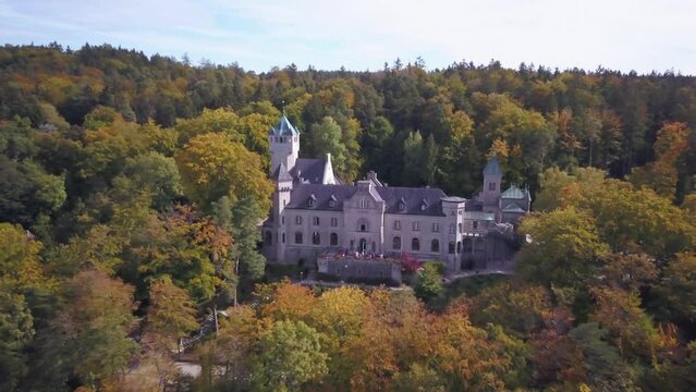Aerial drone cinematic Schloss Seeburg Castle Lake Starnberg Munich Germany Europe near Bavarian alps mid day afternoon autumn fall colors yellow orange deep blue forward pan up reveal movement