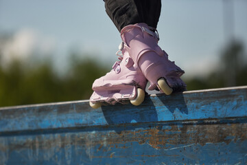 Skater girl grinding on a ledge in a skatepark. Female inline roller blader performing grind trick