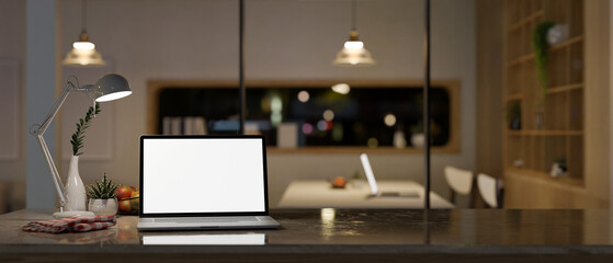 Modern workspace at night with laptop mockup on a table over a modern meeting room.