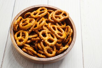 Crunchy pretzels in a black bowl are placed on a wooden table. A perfect salty party snack. copy space. crispy baked salt cookies or biscuits 
