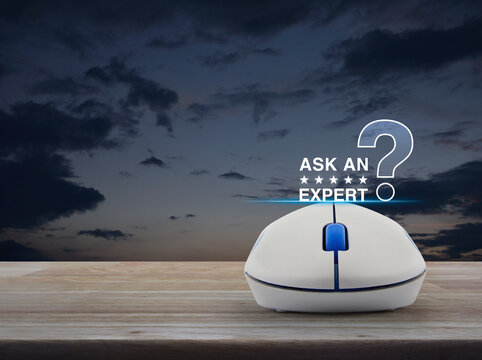 Ask an expert with stars and question mark sign icon with wireless computer mouse on wooden table over sunset sky, Business communication online concept
