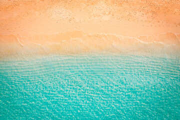 Obraz na płótnie Canvas Summer seascape beautiful waves, blue sea water sunset light. Top view from drone. Seaside aerial scene, amazing tropical nature background. Beautiful bright sea waves splashing golden beach sand
