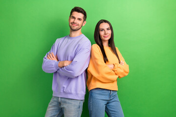 Photo of sweet shiny boyfriend girlfriend wear sweatshirts arms folded smiling isolated green color background