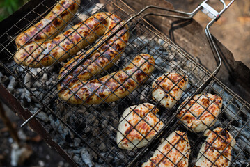 Grilling, frying fresh chicken meat and sausages Close-up.