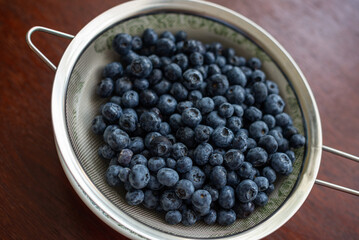 Wild organic blueberries, washed in a sieve, on the table.