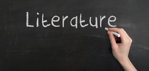 Fototapeta premium A woman's hand write text literature with chalk on chalkboard