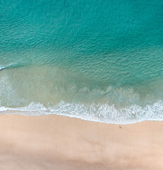Fototapeta na wymiar Aerial view of the ocean with surfers, wave and nice pristine blue water