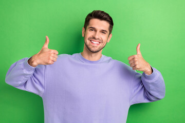 Photo of confident cheerful young man wear purple showing two thumbs up isolated green color...