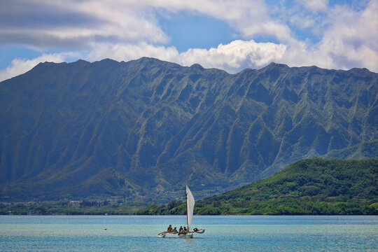 Outrigger canoe sailing in Kaneohe Bay with the Ko'olau mountains the background on the island of Oahu, Hawaii