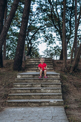 Little blonde girl walking in the park and sitting on the stairs