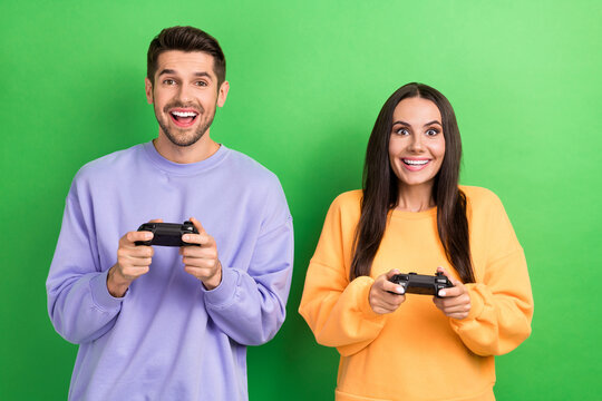 Portrait of two positive funky partners toothy smile enjoy playing video games isolated on green color background