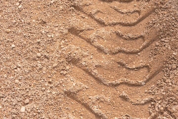 Footprint of car tire tread in a sand gravel road texture. Country road textured background. Backdrop for various ideas. Small stones land. Abstract sandy rough surface. Trendy effect. No people. Tyre