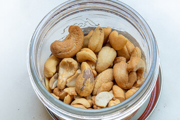 Open jar filled with Brazilian nuts close up, Raw cashews nuts in an open glass jar on t wooden background