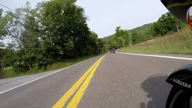 Bikers riding on heavy bikes long curves in a group on an American highway