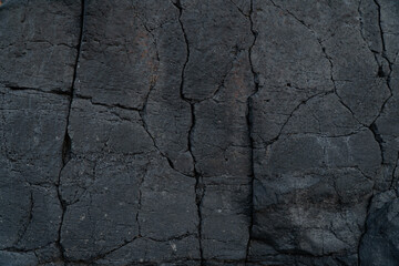 Black volcanic lava bedrock with cracks. Stone background icon.