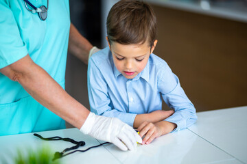 Doctor showing a little kid how to check his blood pressure
