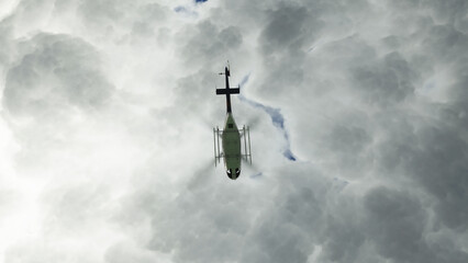 Bottom view of emergency helicopter take flight above city with cloudy gloomy situation and move fast trying to help somebody. © Yu2Pix