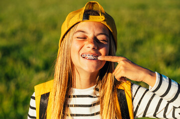 Portrait of beautiful young blonde girl in a yellow cap and a bracket on her teeth.