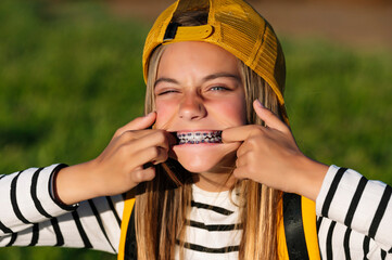 Portrait of beautiful young blonde girl in a yellow cap and a bracket on her teeth.