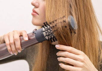 Naklejka premium beautiful young woman using rotative brush hair styler for hair.female girl with long dark blonde hair.smiling woman in mirror.