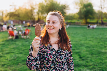 Happy young woman with delicious chocolate ice cream outdoors. Unhealhty food and weight loss...