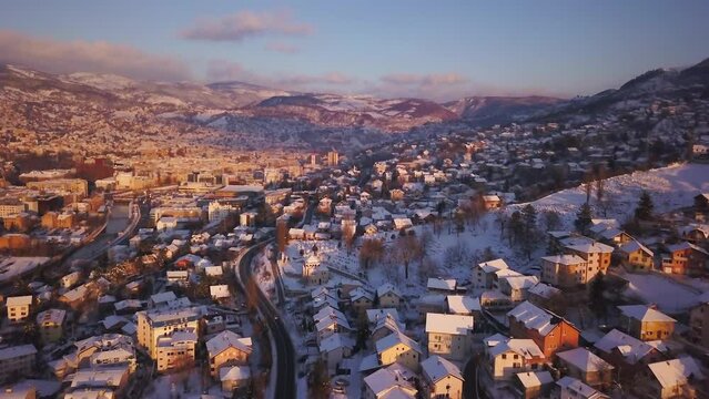 Aerial cinematic drone snowy roads winter Olympic downtown snowy frozen Sarajevo City town center Bosnia and Herzegovina frozen landscape afternoon sunset golden purple backward movement