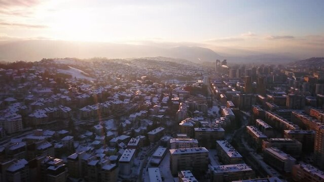 Aerial cinematic drone snowy roads winter Olympic downtown snowy frozen Sarajevo City town center Bosnia and Herzegovina landscape afternoon sunset golden purple circle right movement